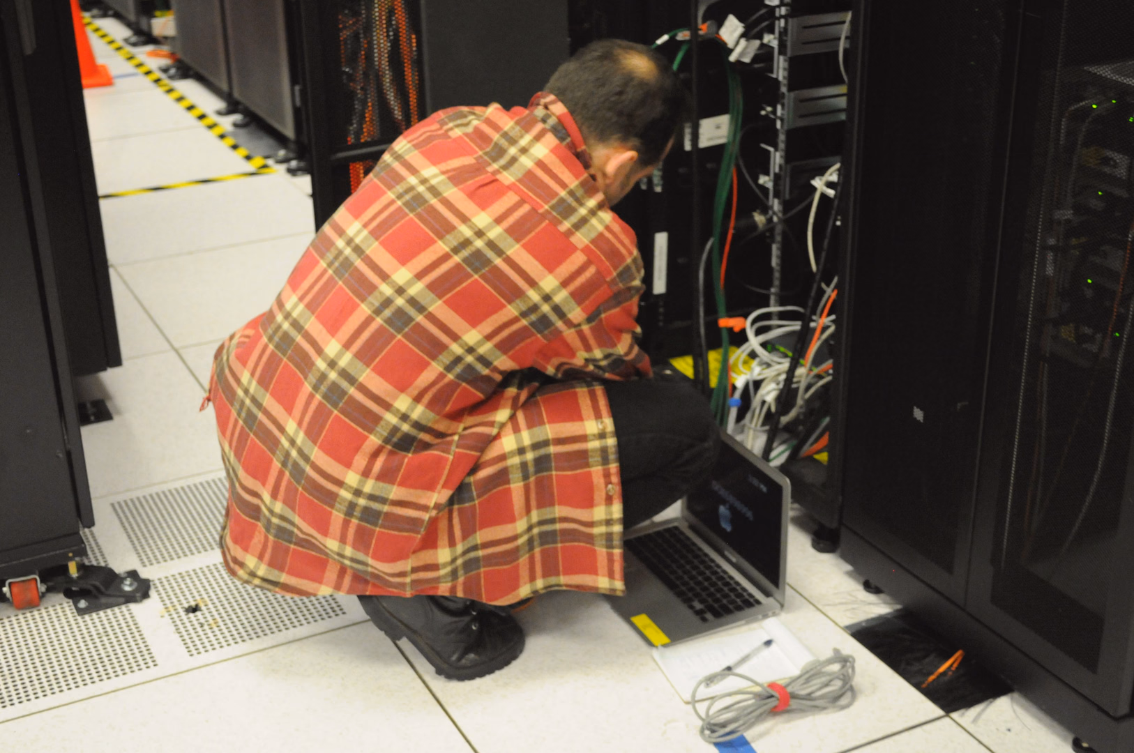 Technician working on server rack in high-performance datacenter for performance and latency optimization.